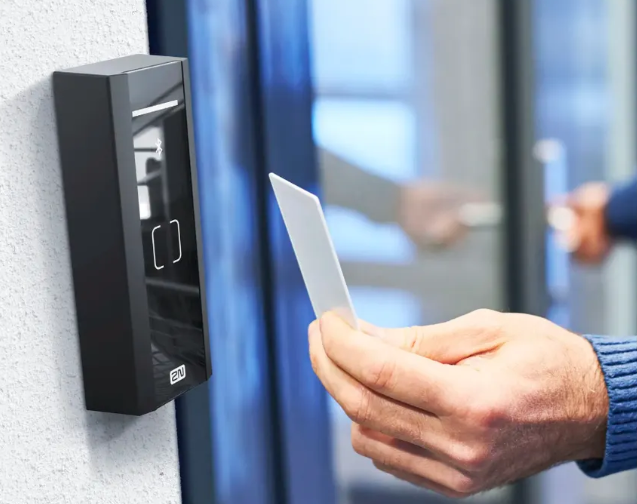 Persona acercando una tarjeta a un lector de control de accesos junto a una puerta