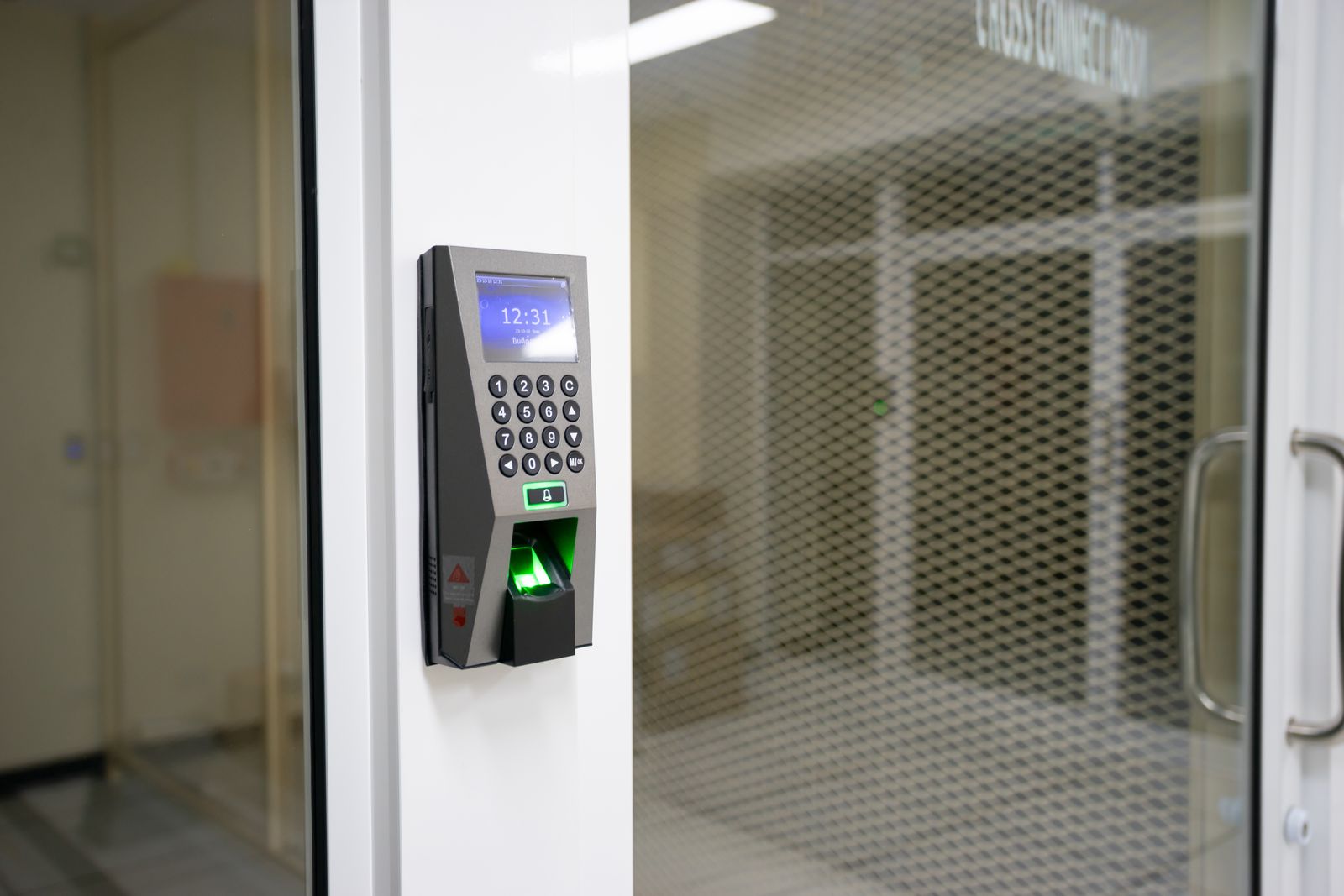 Lector biométrico de huella junto a una puerta de acceso controlado